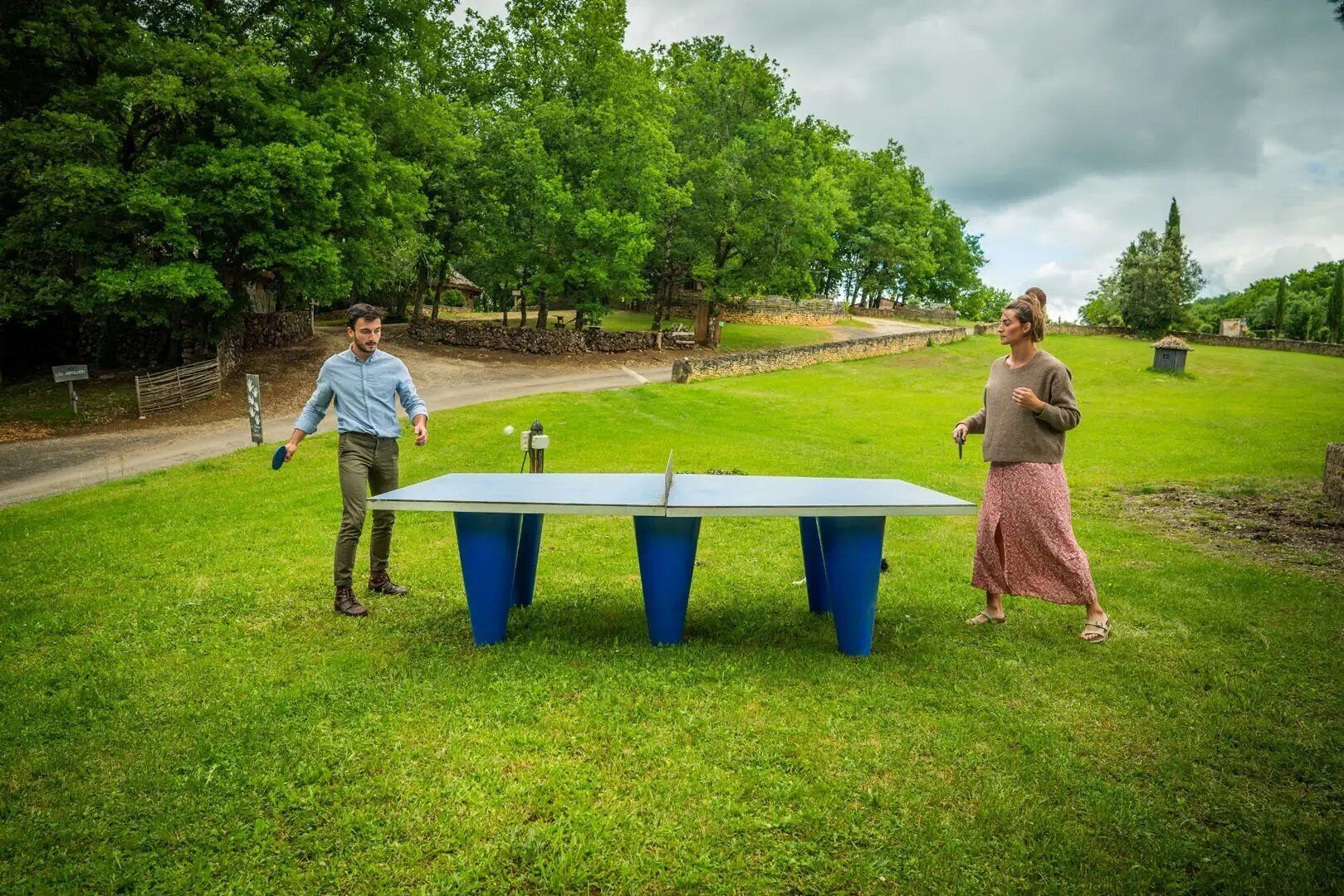 A table tennis table in a grassy outdoor area with trees in the background.