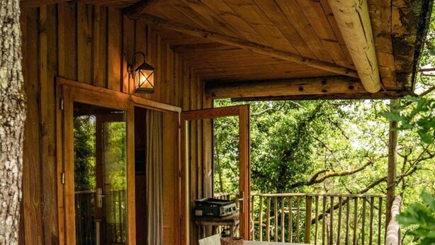 A wooden cabin with a covered porch, a table with chairs, and a view of the surrounding forest. - Cabane 3 étoiles - Piscine  - ccbfh0c (Saint-Amand-de-Coly)