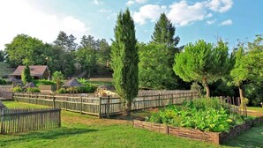 A fenced garden with a tall tree, a wooden fence, and a wooden structure. - Cabane 3 étoiles - Piscine  - ccbfh0c (Saint-Amand-de-Coly)