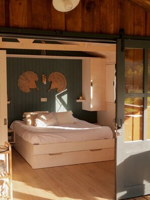 Ein gemütliches Schlafzimmer mit einem Bett, einer Holztür und einem Wandventilator.