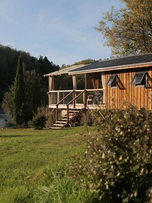 Eine Holzhütte mit verdeckter Veranda und einer Treppe, die zu einer Terrasse führt.
