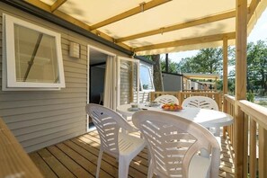 Eine überdachte Terrasse mit Tisch und Stühlen, einem Fenster und einer Tür zu einem Gebäude.