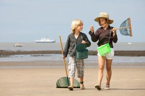 Zwei Personen am Strand, im Hintergrund ein Boot.
