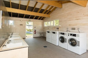 A laundry room with a wooden ceiling, a fire extinguisher, and a view of the outside. - Camping 4 étoiles - Piscine  - ccbffda (Saint-Sulpice-de-Royan)