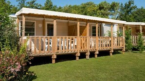A row of wooden mobile homes with a covered porch and a grassy lawn. - Camping 4 étoiles - Piscine  - ccbffdb (Saint-Sulpice-de-Royan)
