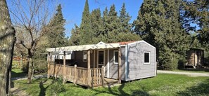 Eine kleine Hütte mit Veranda, umgeben von Bäumen.