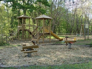 Ein Spielplatz mit Holzkonstruktionen, darunter eine Rutsche und Kletterelemente.