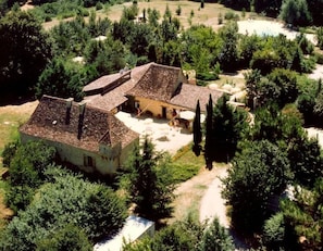 A traditional building with a tiled roof, surrounded by dense greenery and a clear sky. - Camping 3 étoiles - Piscine  - ccbg0d0 (Molières)