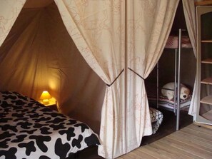 Ein zeltähnliches Zimmer mit Bett, Lampe und Stofftier.