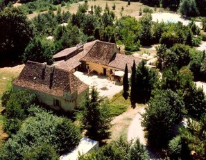 Ein traditionelles Gebäude mit Ziegeldach, umgeben von üppiger Vegetation und blauem Himmel.