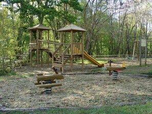 Ein Spielplatz mit Holzkonstruktionen, darunter eine Rutsche und Kletterelemente.