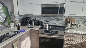 Een moderne keuken met een roestvrijstalen magnetron, een koffiezetapparaat en een waterkoker op het aanrecht.