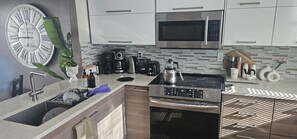 Eine moderne Küche mit Mikrowelle aus Edelstahl, einer Kaffeemaschine und einem Wasserkocher auf der Arbeitsfläche.