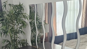 Een moderne kamer met een donker houten dressoir, een grote spiegel en een potplant.