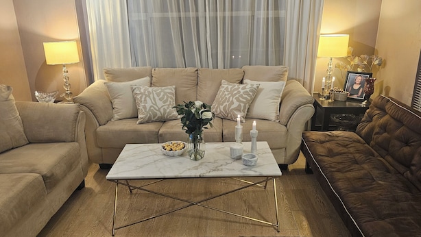Een woonkamer met een beige bank, een bijzettafeltje en een bruine bank.