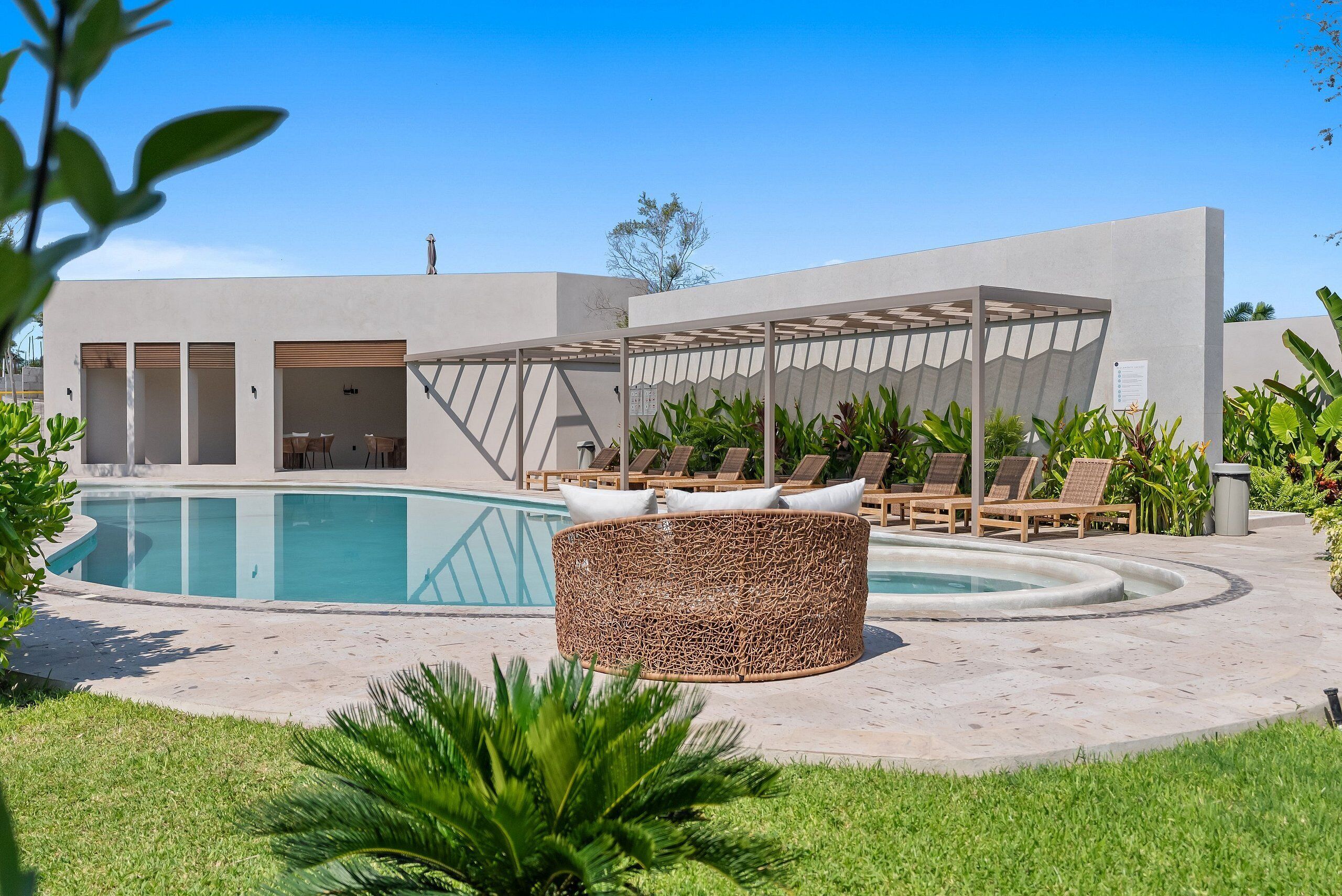 A pool area with lounge chairs and a covered seating area.