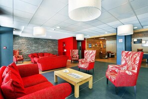 A lobby with red sofas, patterned armchairs, a wooden coffee table, and a stone wall. - 300m from resort center, fitness, sauna, hammam, terrace, balcony, tv, ski locker, 75m² (Briançon)