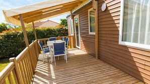 Eine Holzterrasse mit überdachter Sitzgelegenheit, einem Fenster und einer Tür.