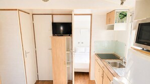 Eine kompakte Küche mit integriertem Fernseher, einer Mikrowelle und einem Kühlschrank.