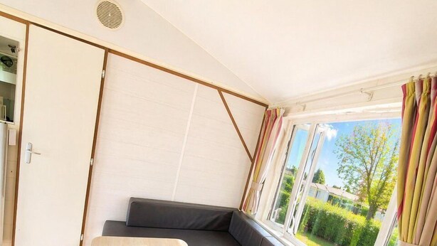 Ein modernes Interieur mit einem Holztisch, einer Couch und einem Fenster mit Vorhängen.