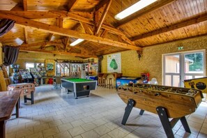 Ein Innenraum mit Holzboden, Billardtisch, Kicker und Poolbillard.
