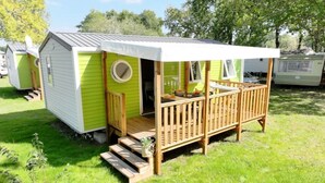 Una casa móvil pequeña de un solo piso, con un porche y una pequeña terraza.