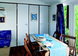Ein Essbereich mit Tisch für vier Personen, Stühlen, einer blauen Tischdecke und Blick auf Grün.