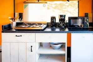 Eine Küche mit Gasherd, Kaffeemaschine, Mikrowelle und Kochgeschirr.
