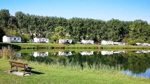 Vistes al llac amb una panxa, cases mòbils blanques i un turó boscós.