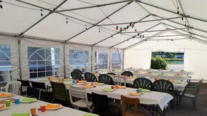 Una zona de menjador coberta amb tendes, taules preparades per a diverses persones, cadires i vista a l'exterior.