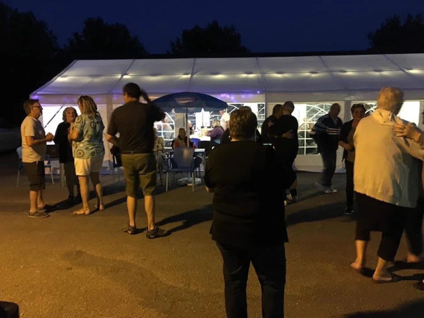 A group of people gathered outside a tented structure at night.