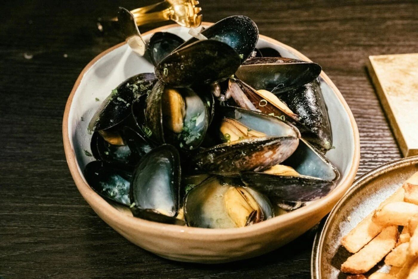 A bowl of mussels on a wooden table.