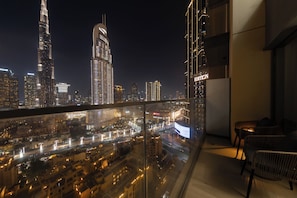 A high-rise building with a view of a cityscape at night, including illuminated skyscrapers and a busy street below. - Spacious 2BR with Burj Khalifa View (Dubai)