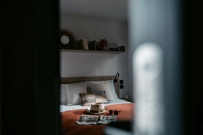 Ein Schlafzimmer mit einem Bett, einem Nachttisch, einer Lampe und einem Regal mit Büchern und Dekoration.