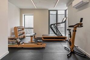 A modern gym with a rowing machine, a treadmill, and a stationary bike. - Hidden 15- Garden Hot Tub (St Ives)