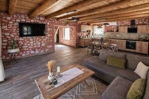 Ein geräumiges Wohnzimmer mit Steinwand, Holzboden, einer Couch und einem Couchtisch.