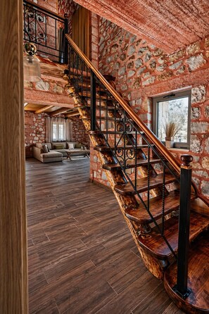 Eine Wendeltreppe mit Holzsitzstufen und schwarzen Geländern in einem Raum mit freiliegenden Steinwänden und Holzboden.