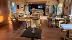 Ein Restaurant mit mehreren Tischen, Stühlen, Holzwänden und einem Küchenbereich im Hintergrund.