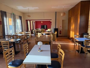 A spacious dining area with multiple tables and chairs, a television, and a fireplace. - Camping 3 étoiles - Piscine  - ccbfig0 (Saint-Fort-sur-Gironde)