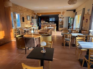 Un restaurante con varias mesas y sillas, paredes de madera y una zona de cocina al fondo.