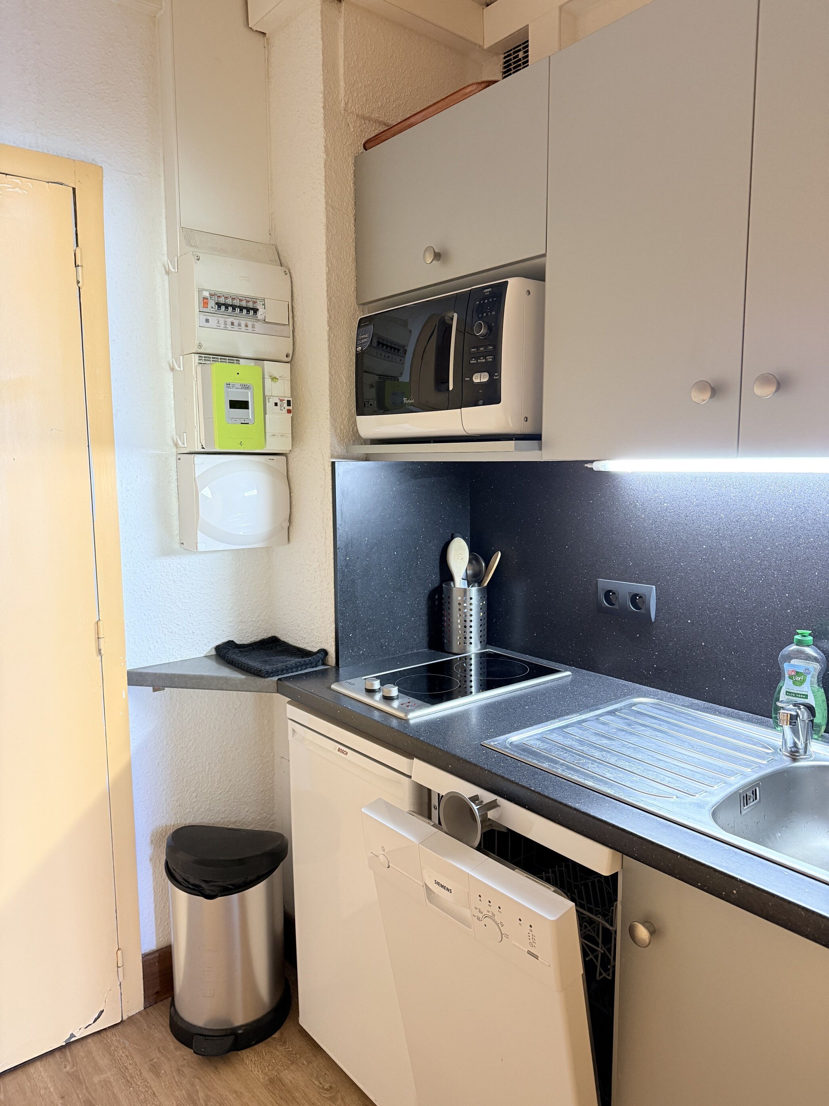 A compact kitchen with a microwave, a sink, and a dishwasher.