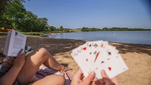 Two people sitting on a sandy beach, one holding a deck of cards. - Camping 3 étoiles - ccbfigd (Ombrée d'Anjou)