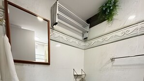 A bathroom with a green sink, a toilet, a mirror, and decorative wall tiles. - Suite Premium (Medellín)