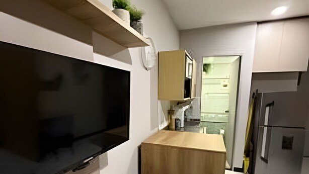 A modern kitchen with a built-in TV, wooden cabinets, and a small island. - Suite Premium (Medellín)