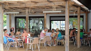An outdoor patio with wooden beams, metal chairs, and tables.