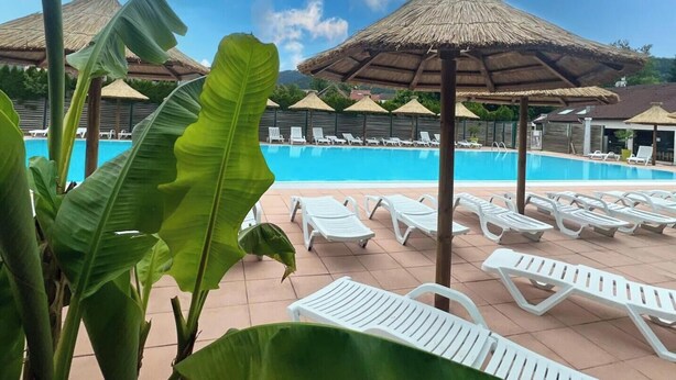 A pool area with lounge chairs and thatched umbrellas.