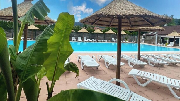 A pool area with lounge chairs and thatched umbrellas.
