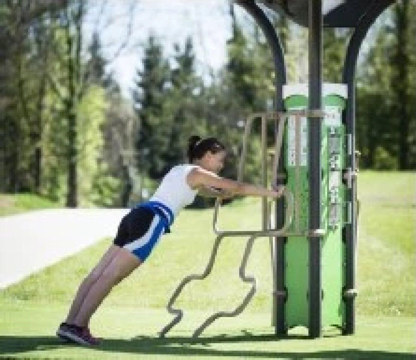 Una persona usando una máquina de ejercicios verde al aire libre.