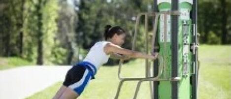Una persona usando una máquina de ejercicios verde al aire libre.