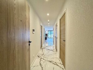 A hallway with wooden doors, a marble floor, and recessed lighting. - 2nd floor, terrace, tv, 75m², Serre Chevalier (Briançon)